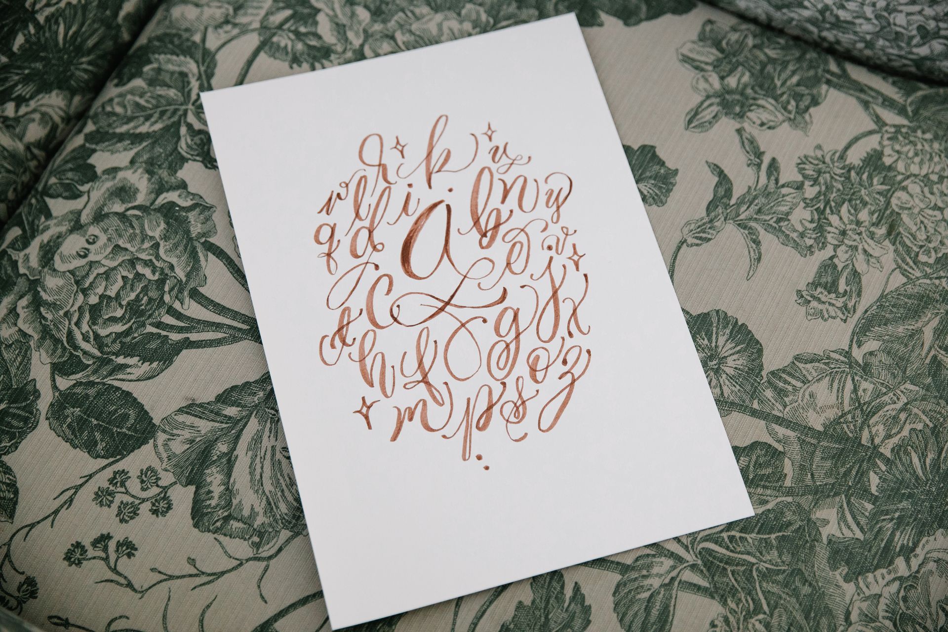 A White Printer Paper with Alphabet Letters on Floral Textile