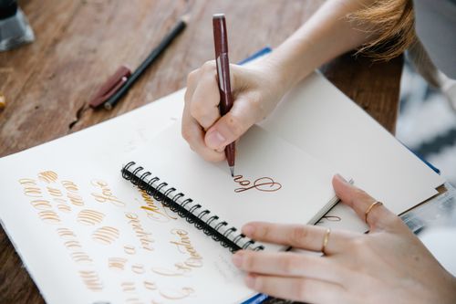 Hand lettering practice in a spiral sketchbook — photo by Katya Wolf on Pexels