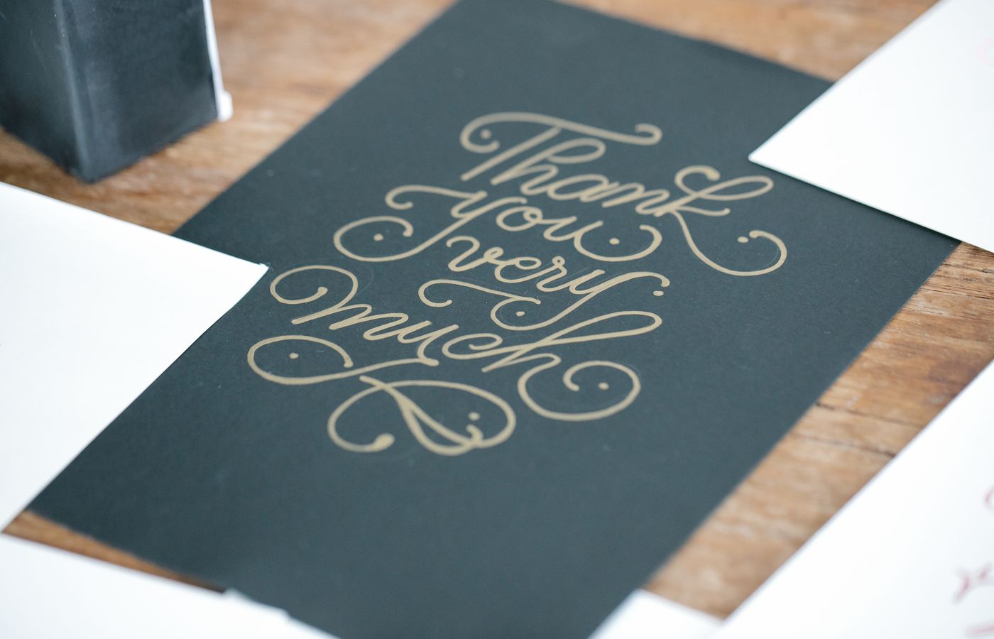 Close-up of a stylish thank you card with handwritten script on a wooden table.
