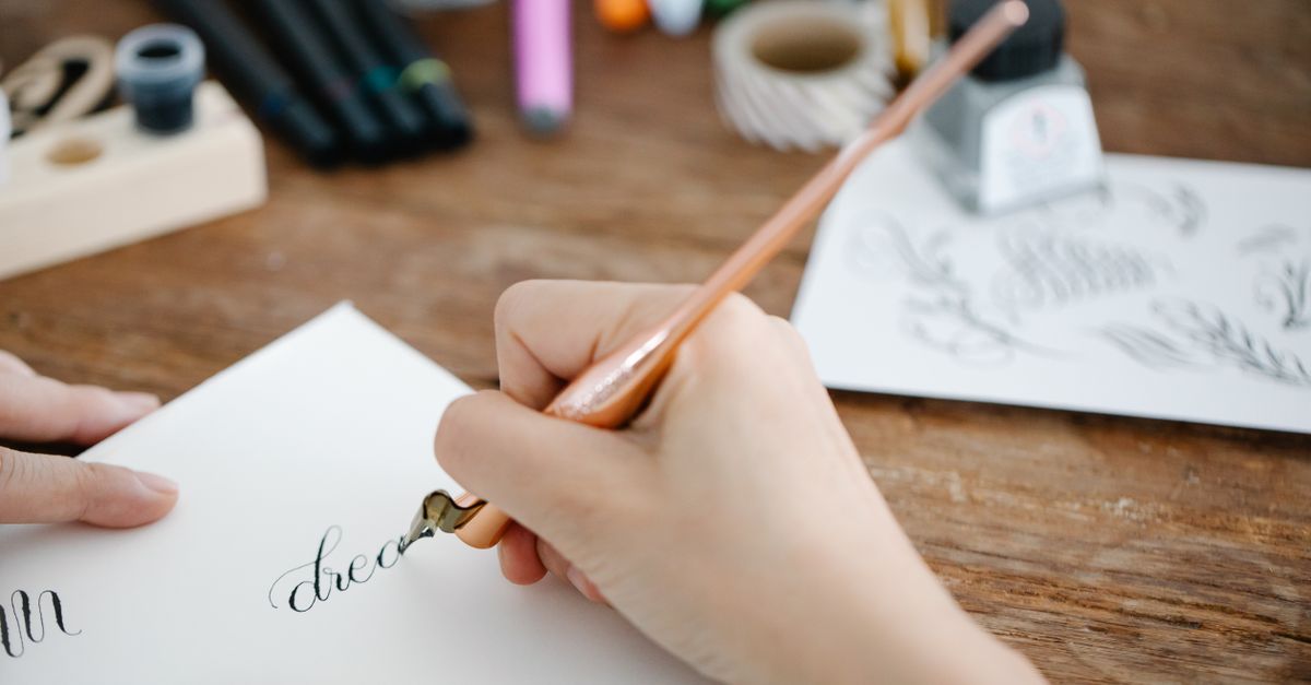 Person Writing Using a Copper Ink Pen · Free Stock Photo