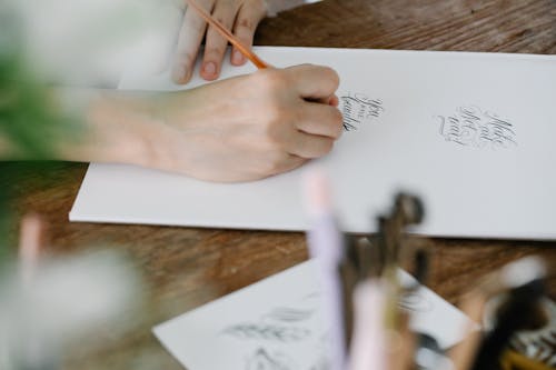 Hand of a Person Writing on White Paper