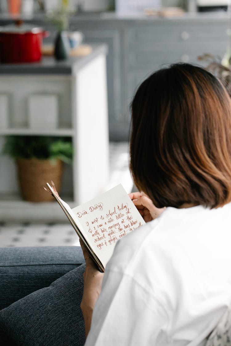 Back View Of Woman Sitting On A Couch And Reading 