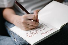 Person writing in a notebook with elegant handwritten calligraphy.