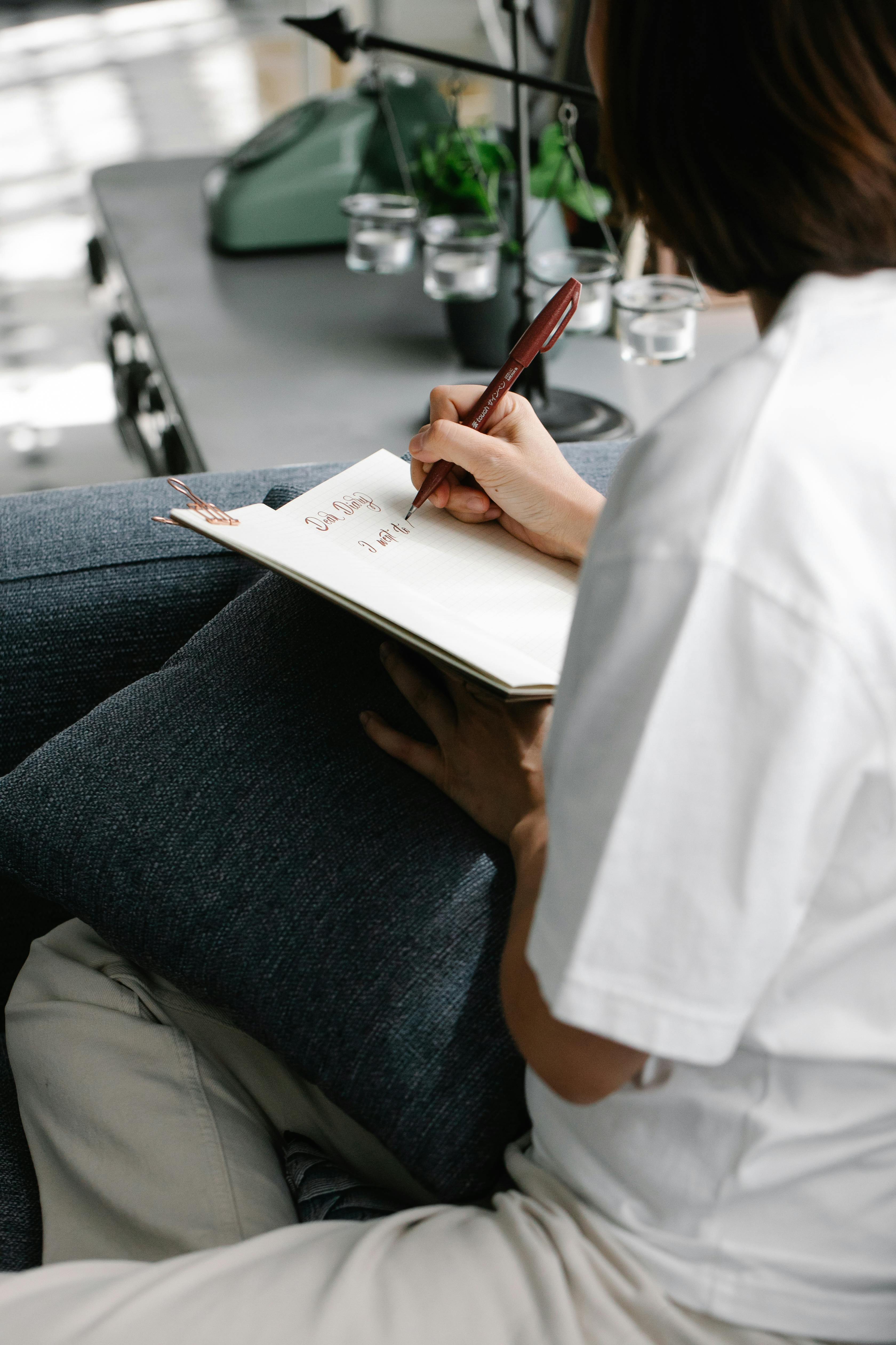 Person in White Shirt Writing on a Notebook · Free Stock Photo