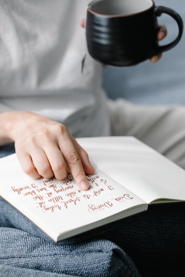 Person Reading A Journal And Drinking Tea