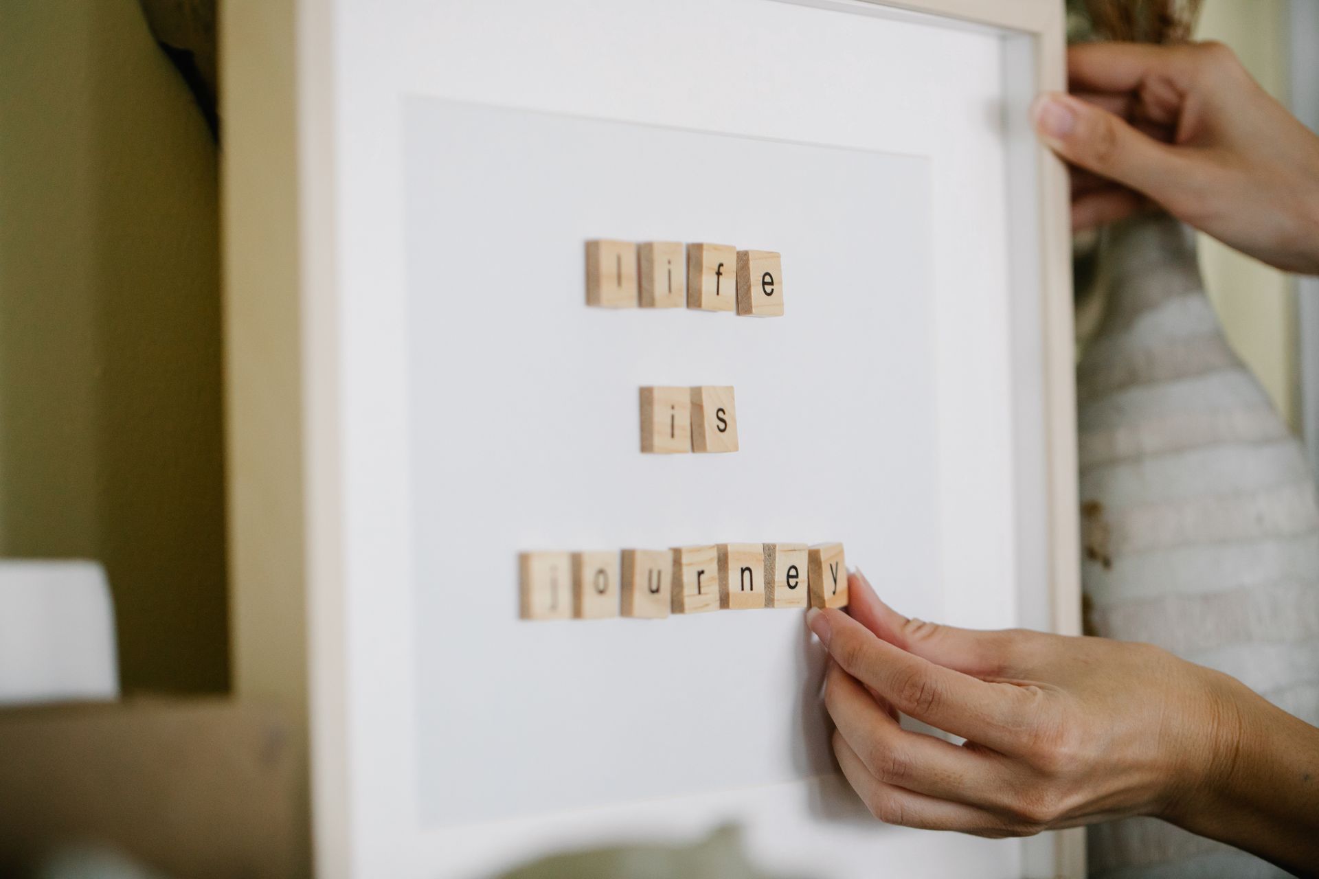 Decorative frame with wooden tile quote 'Life is Journey' being held.