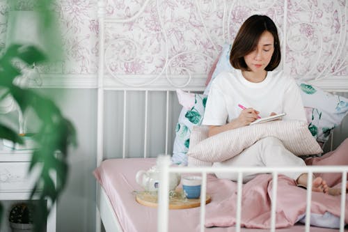 Free A Woman Journaling while Sitting in Bed Stock Photo