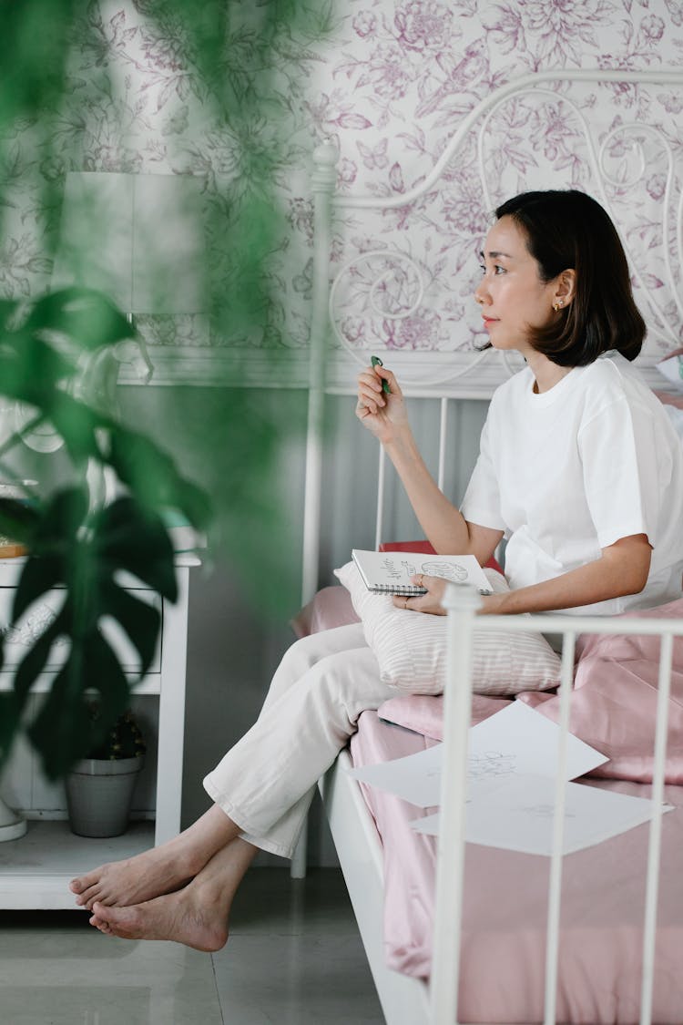 Woman Sitting On The Bed And Holding A Journal 