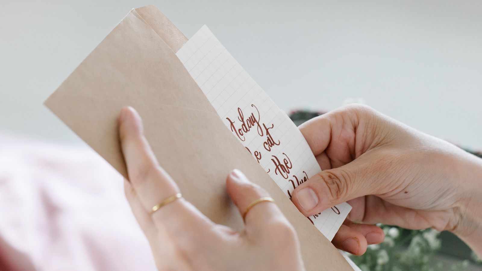 Hands holding a handwritten note and a brown envelope