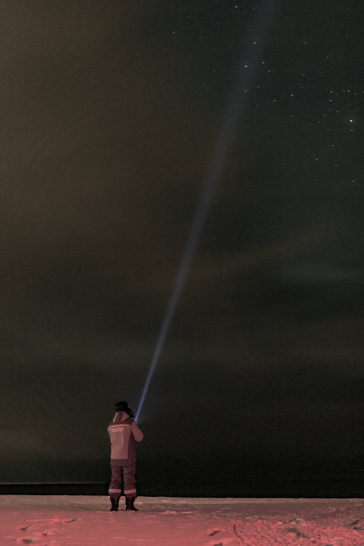 Man In Darkness Using A Powerful Flashlight 