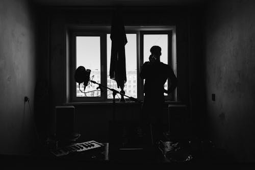 Silhouette of Person Standing Near Windows