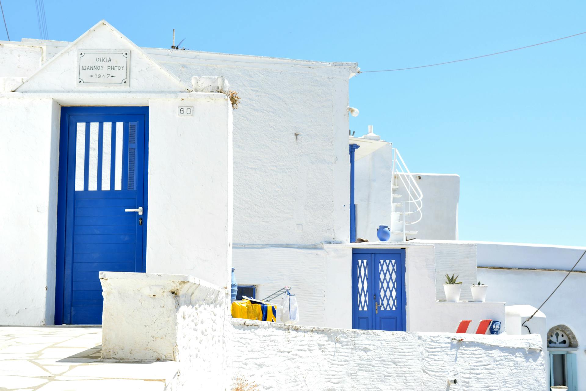 Charming whitewashed Cycladic architecture with vibrant blue doors under a clear sky in Tinos, Greece.