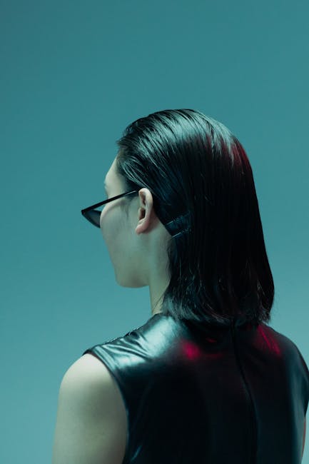 A woman in dark sunglasses and a leather top faces away, evoking a cool and mysterious vibe.