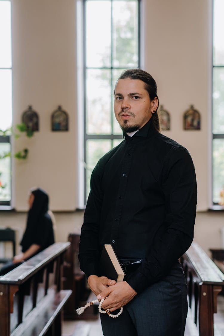 Pastor In Black Clothes Holding A Bible