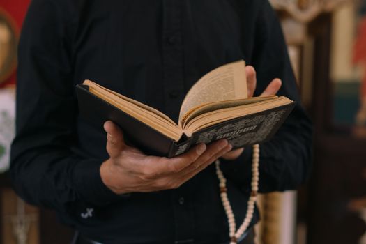 A person holding an open book with wooden prayer beads, emphasizing spirituality and introspection.