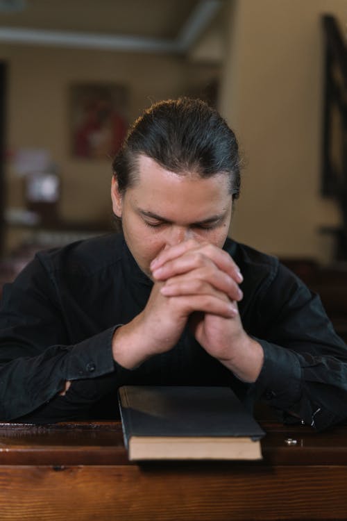 Man Kneeling on Church Pew while Praying