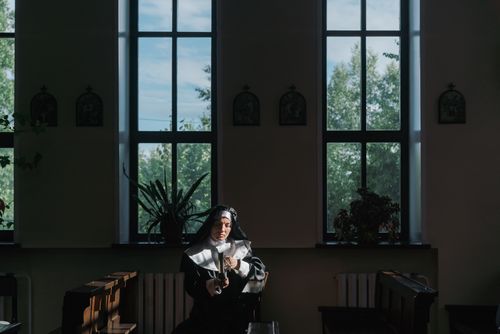 Free Nun in a tranquil church setting, reading and reflecting in afternoon light. Stock Photo