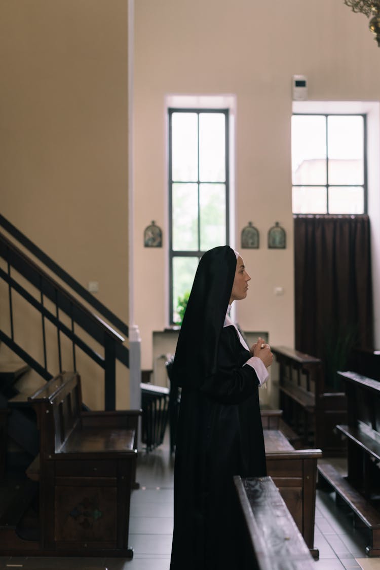 A Nun Standing Near The Church Empty Pews