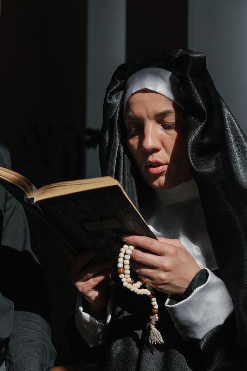 Free A nun reads a Bible in a moment of prayer and contemplation, holding a rosary. Stock Photo