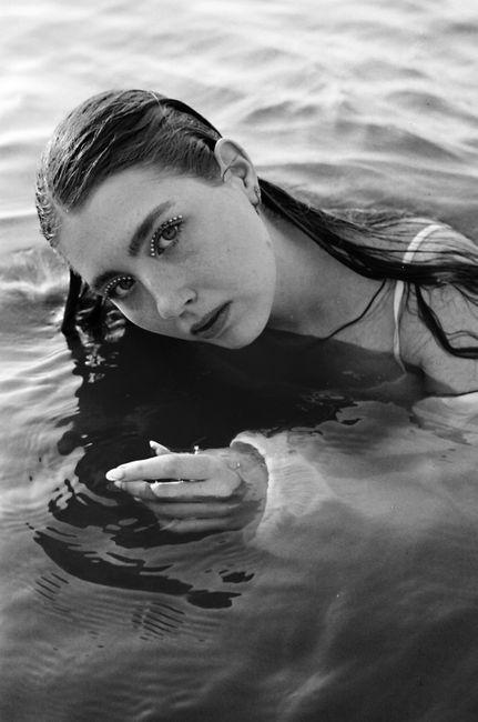 Black and white portrait of a woman with makeup, partially submerged in water.