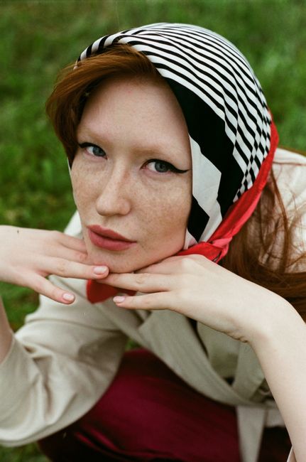 A striking portrait of a woman wearing a striped head scarf in an outdoor setting.