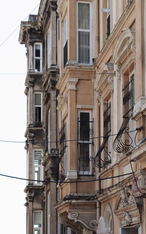 Free Elegant facade of a historic European building featuring detailed wrought iron balconies and classic architecture style. Stock Photo