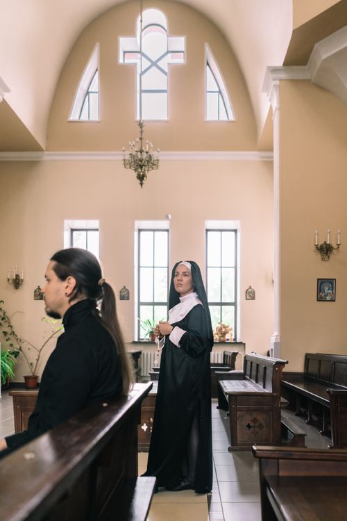 Free Nun and priest within a modern church, featuring natural light and religious symbols. Stock Photo