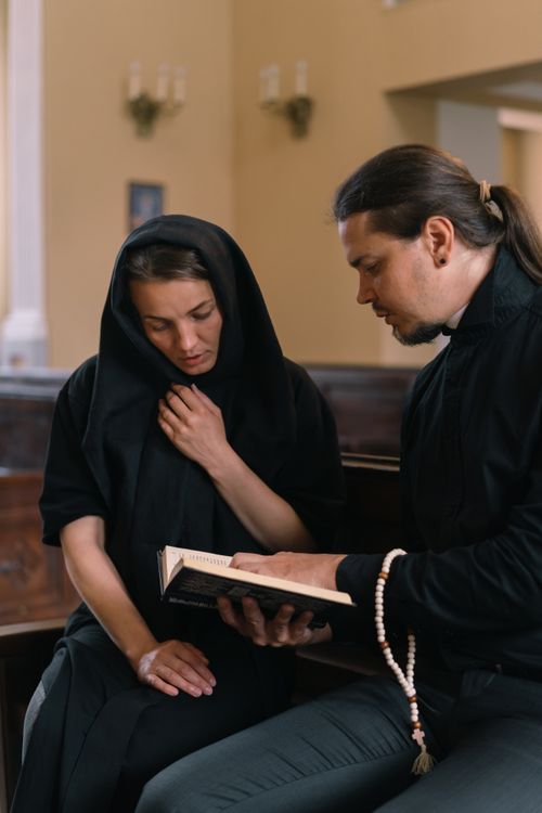 Free A man and woman in black attire engaged in a spiritual reading with prayer beads indoors. Stock Photo