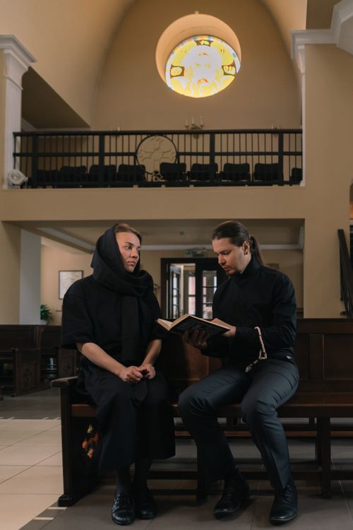 Free A priest and a woman in a church, reading and reflecting on the holy bible. Stock Photo