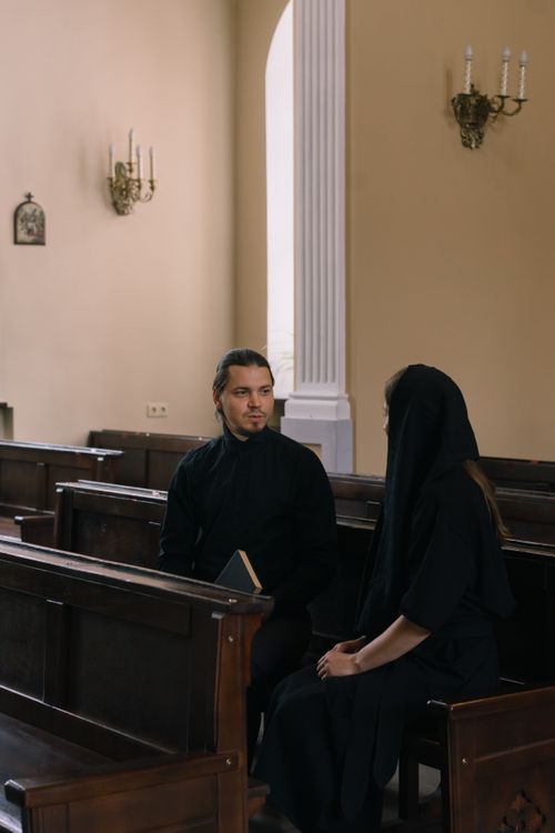 Free A priest and parishioner engaged in a spiritual conversation inside a church. Stock Photo