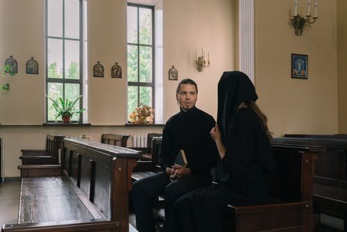 Free A priest discussing with a parishioner in a peaceful church setting. Stock Photo