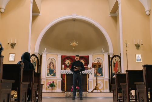 Free Pastor reading a religious book at a church altar with icons and pews. Stock Photo