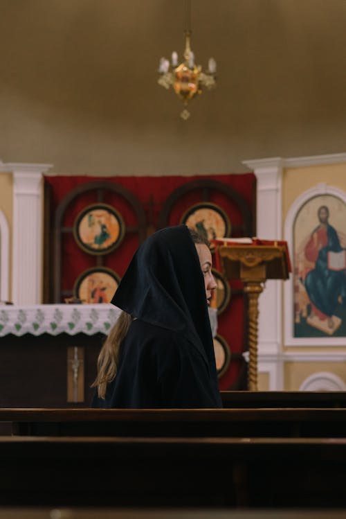 A Woman with Black Scarf on Head Sitting inside a Church