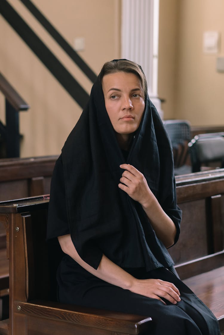 Woman In Black Head Scarf Sitting On Church Pew