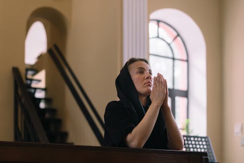 A Woman Praying with Her Hands Together inside a Church