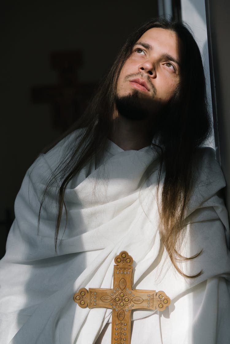 Man In White Clothes Holding A Cross