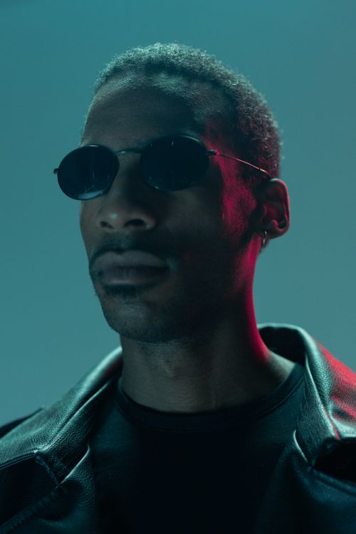 Free Close-up of a man in sunglasses with cyberpunk lighting, creating a futuristic mood. Stock Photo