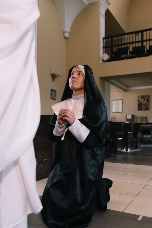Free A devout nun kneeling in prayer inside a church, showcasing faith and devotion. Stock Photo