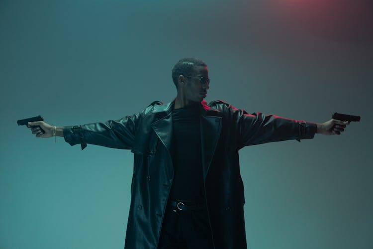 Man In A Leather Coat Holding Guns 