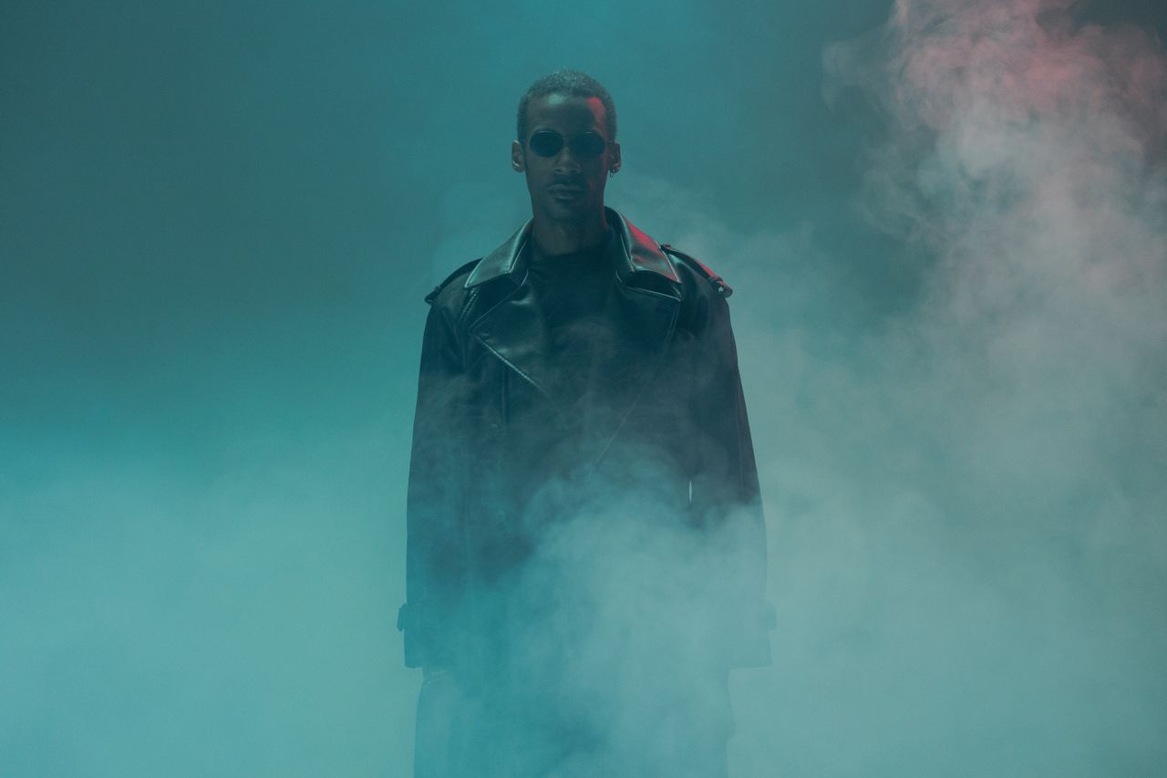a dramatic portrait of a man in a leather jacket surrounded by smokey