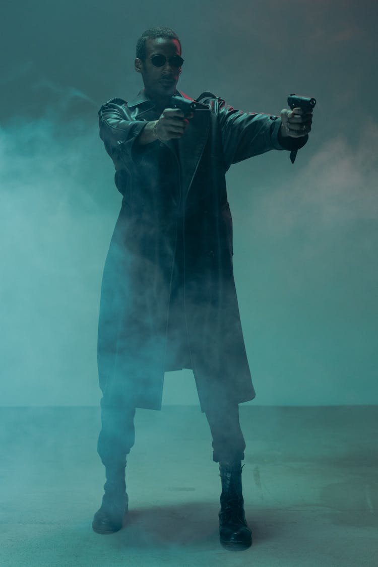 Man In Black Trench Coat Holding Two Handguns