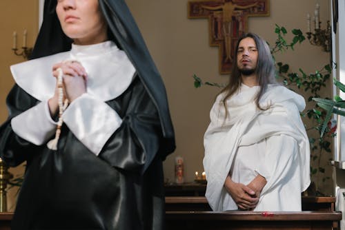 A Man Standing Behind a Nun Praying