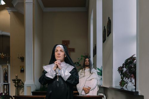 Free A nun in prayer holds rosary beads in a church, symbolizing devotion and faith. Stock Photo