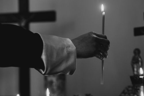 Free A close-up of a hand holding a lighted candle in a religious ceremony, focused on the serene act of worship. Stock Photo