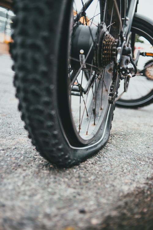 Free Detailed view of a bicycle wheel with a flat tire on a road surface. Stock Photo