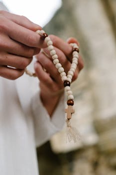 Close-up of hands holding rosary beads, symbolizing faith and spirituality.