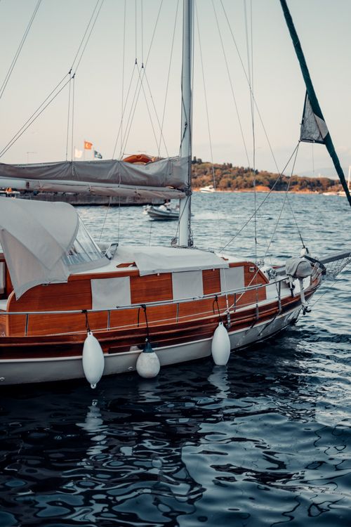 Free Beautiful wooden sailboat gliding through calm waters at sunset, evoking a sense of adventure and serenity. Stock Photo