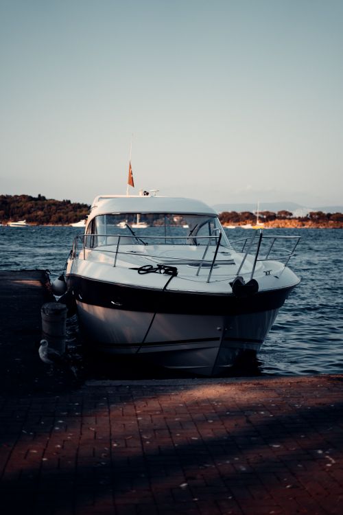 Free Elegant yacht docked at a picturesque harbor during a serene seaside sunset. Stock Photo
