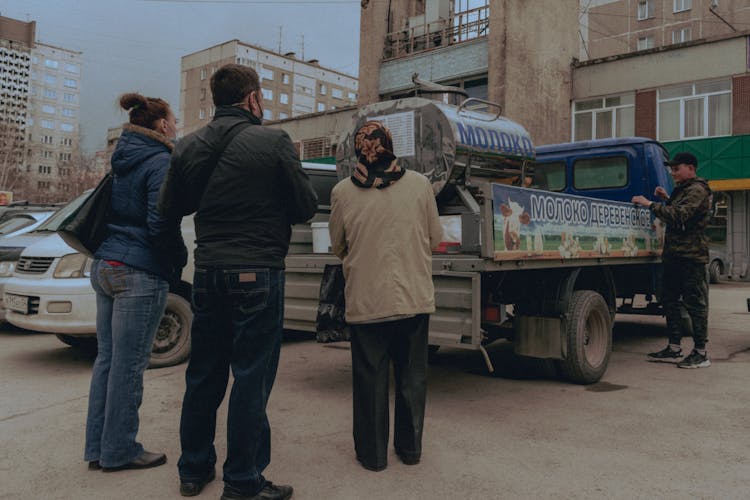 People Standing In Line To Buy Milk From A Local Supplier 