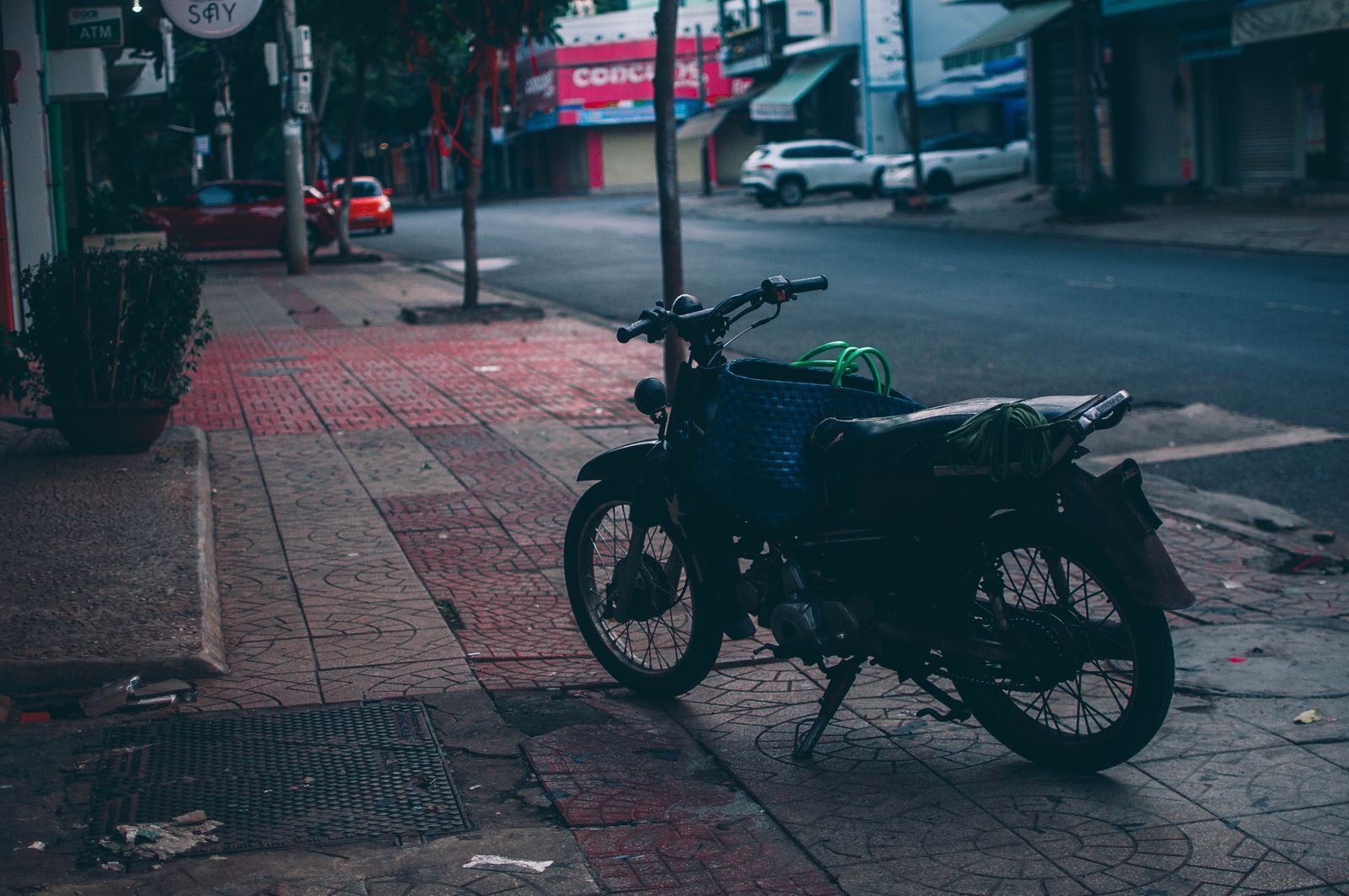 Moto posée sur un trottoir carrelé en milieu urbain au crépuscule